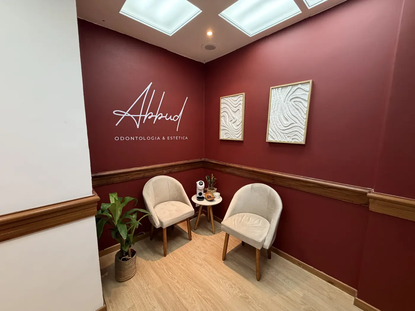 Recepção da clínica Abbud, com parede bordô e a assinatura Abbud Odontologia e Estética
